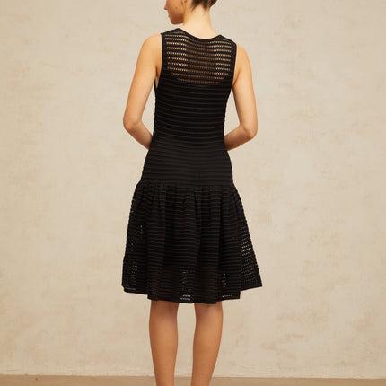 A black mini dress with a flounced hem and pointelle knit pattern featuring a fitted silhouette and short sleeves
