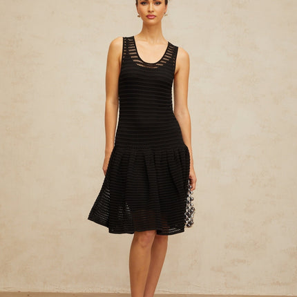 A black mini dress with a flounced hem and pointelle knit pattern featuring a fitted silhouette and short sleeves
