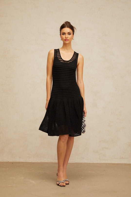 A black mini dress with a flounced hem and pointelle knit pattern featuring a fitted silhouette and short sleeves