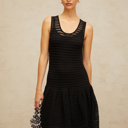 A black mini dress with a flounced hem and pointelle knit pattern featuring a fitted silhouette and short sleeves