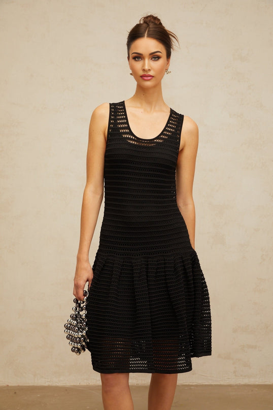 A black mini dress with a flounced hem and pointelle knit pattern featuring a fitted silhouette and short sleeves