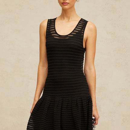 A black mini dress with a flounced hem and pointelle knit pattern featuring short sleeves and a fitted silhouette