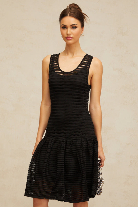 A black mini dress with a flounced hem and pointelle knit pattern featuring short sleeves and a fitted silhouette