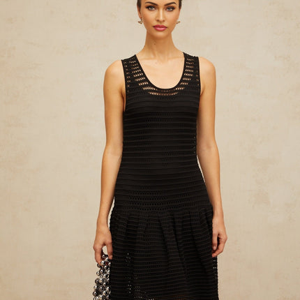 A black mini dress with a flounced hem and pointelle knit pattern featuring short sleeves and a fitted silhouette