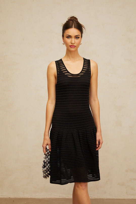 A black mini dress with a flounced hem and pointelle knit pattern featuring short sleeves and a fitted silhouette