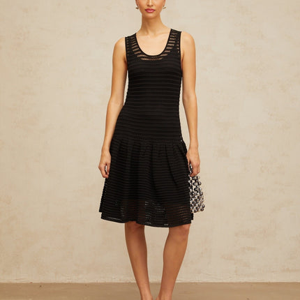 A black mini dress with a flounced hem featuring pointelle knit detailing and a fitted silhouette