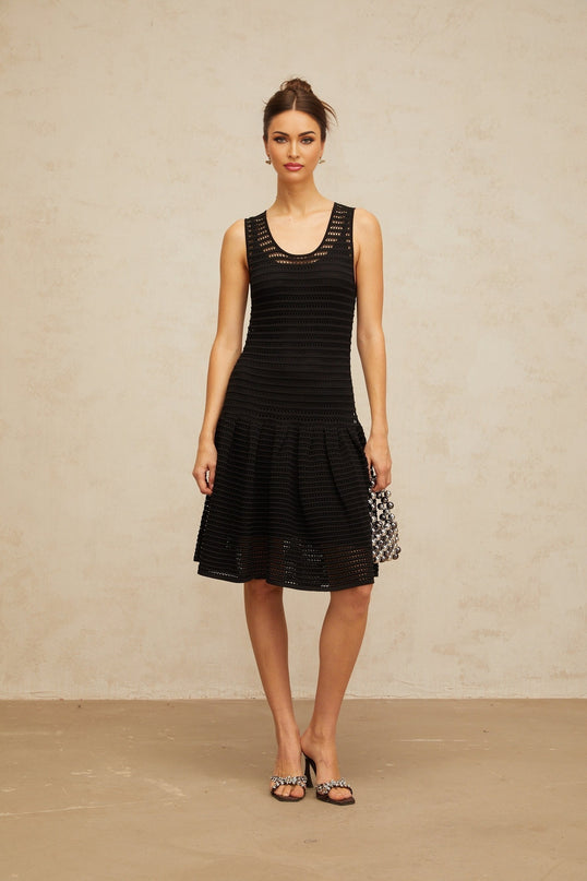 A black mini dress with a flounced hem featuring pointelle knit detailing and a fitted silhouette