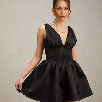 A black mini dress with a Vneck and flared skirt styled on a model