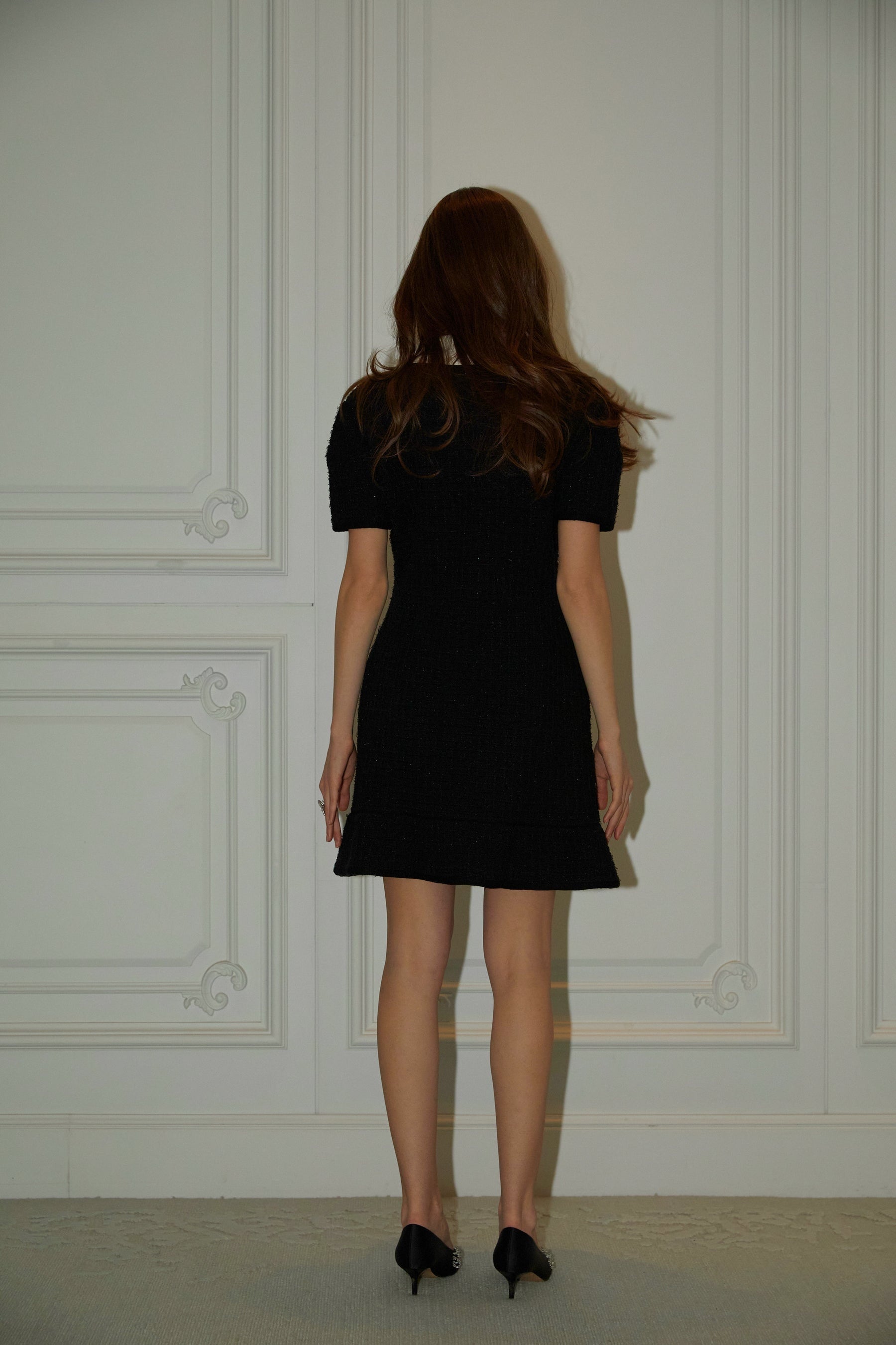 A black mini dress with a waffle knit texture featuring embellishments worn by a model named Ava