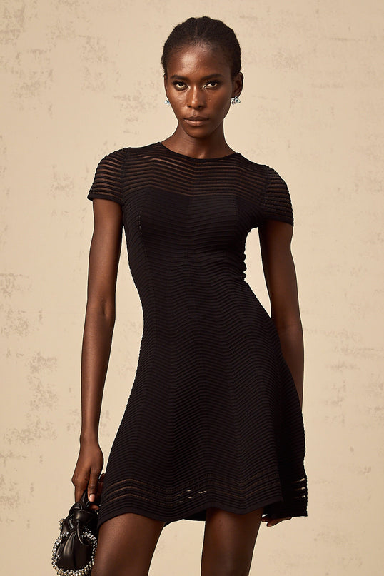 A black mini dress with a wavy crochet texture and short length featuring an intricate textured pattern throughout the garment