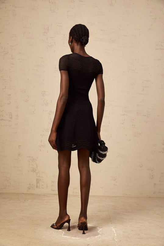 A black mini dress with a wavy crochet texture named Melisande shown on a model or mannequin