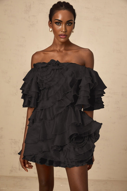 A black mini dress with an asymmetric design featuring a cerise flounce detail and a short hemline