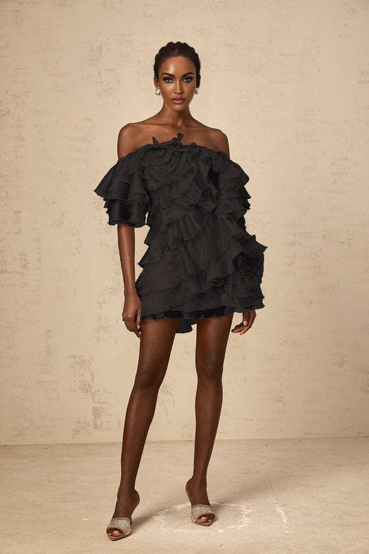 A black mini dress with an asymmetric design featuring a cerise pink flounce detail