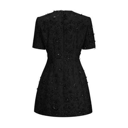 A black mini dress with floral applique embellishments featuring a celestial inspired design