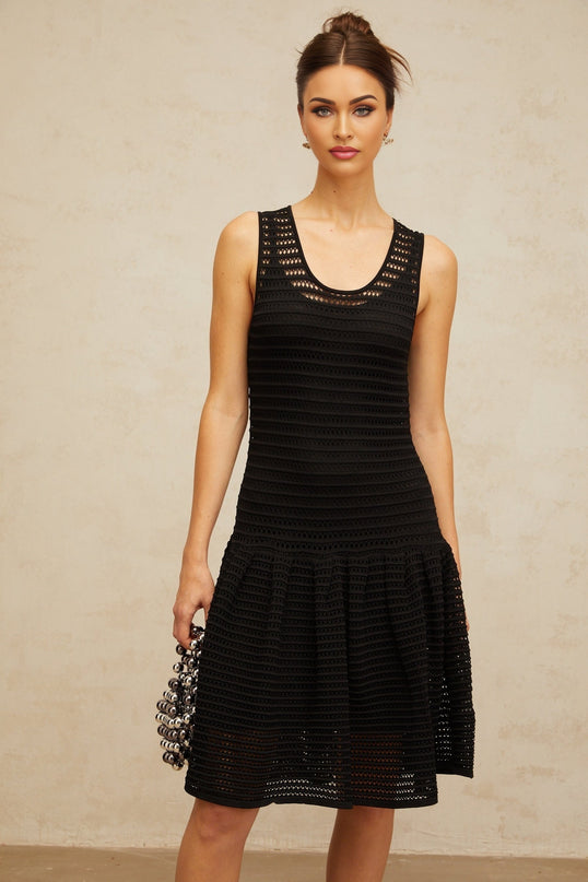 A black mini dress with flounced details and pointelle knit fabric featuring a short hemline and textured pattern