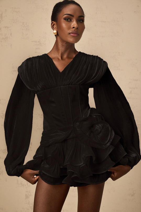 A black mini dress with full pleats and a cinched waist worn by a female model