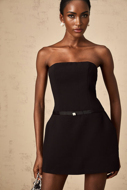 A black mini dress with puffed sleeves and a prominent bowknot detail named Clothilde