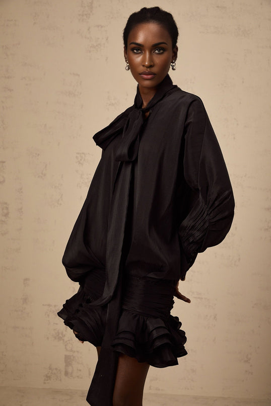 A black mini dress with ruffled details and a pussy bow neckline named Melanie