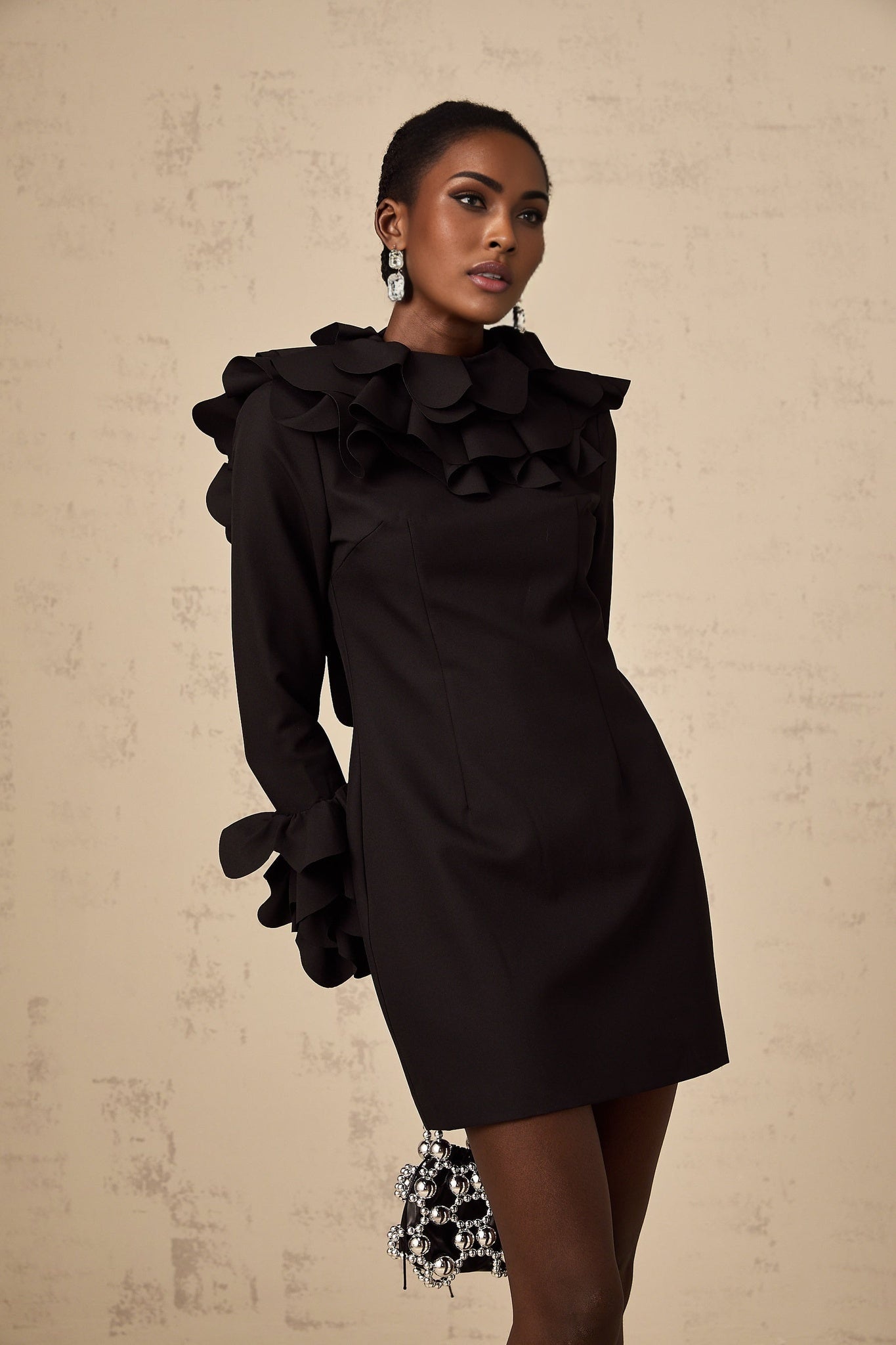 A black mini dress with ruffled details and an open back design named Jacques