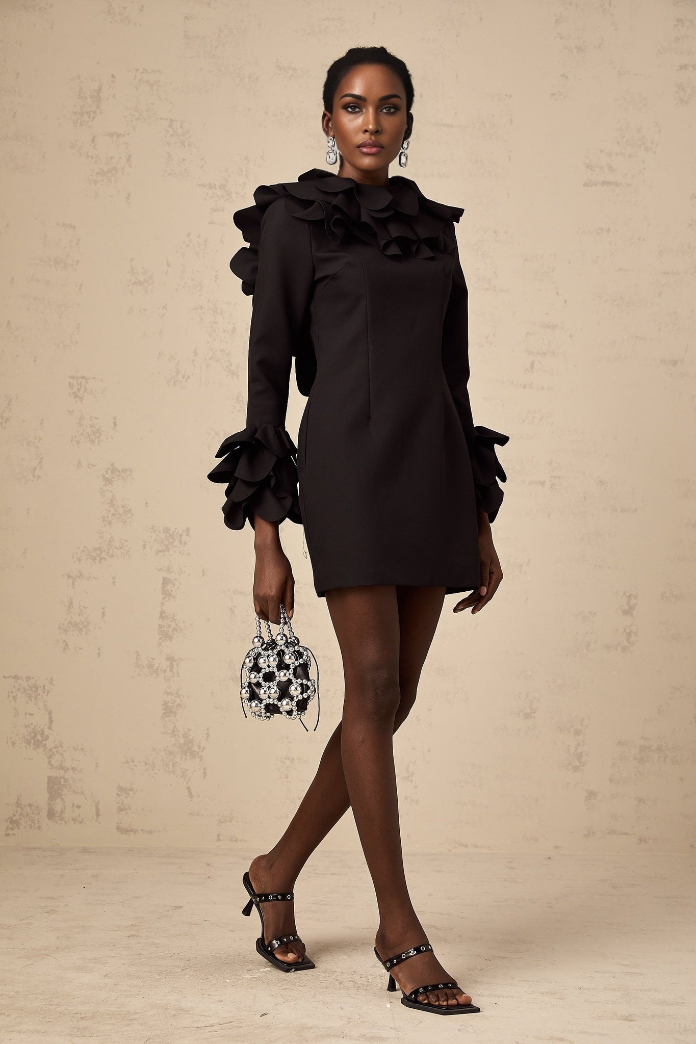 A black mini dress with ruffled details and an open back design named Jacques