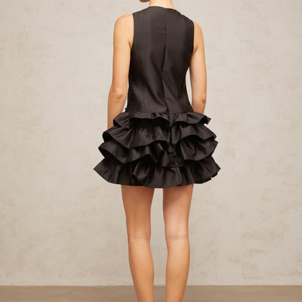 A black mini dress with ruffled tiers and a short hemline featuring a feminine design named Therese