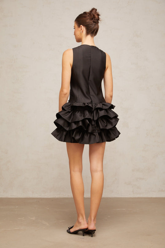 A black mini dress with ruffled tiers and a short hemline featuring a feminine design named Therese