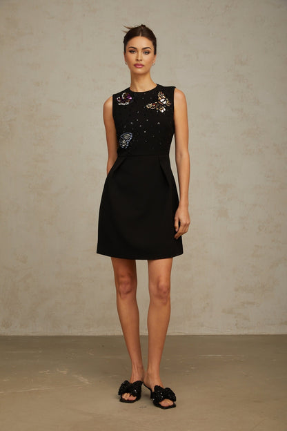 A black mini dress with sequin embellishments featuring a butterfly design worn by a model against a plain background