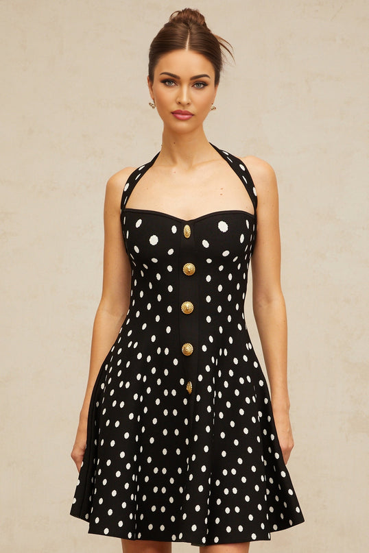A black mini dress with white polka dots and a knit texture worn by a model standing against a plain background