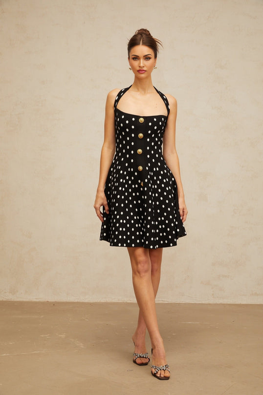 A black mini dress with white polka dots made from knit fabric featuring a fitted silhouette and short length