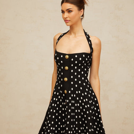 A black mini dress with white polka dots made of knit fabric featuring a fitted silhouette and short hemline