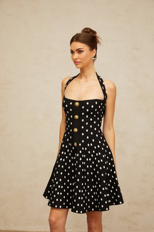 A black mini dress with white polka dots made of knit fabric featuring a fitted silhouette and short hemline