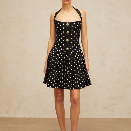 A black mini dress with white polka dots made of knit fabric featuring short sleeves and a fitted silhouette