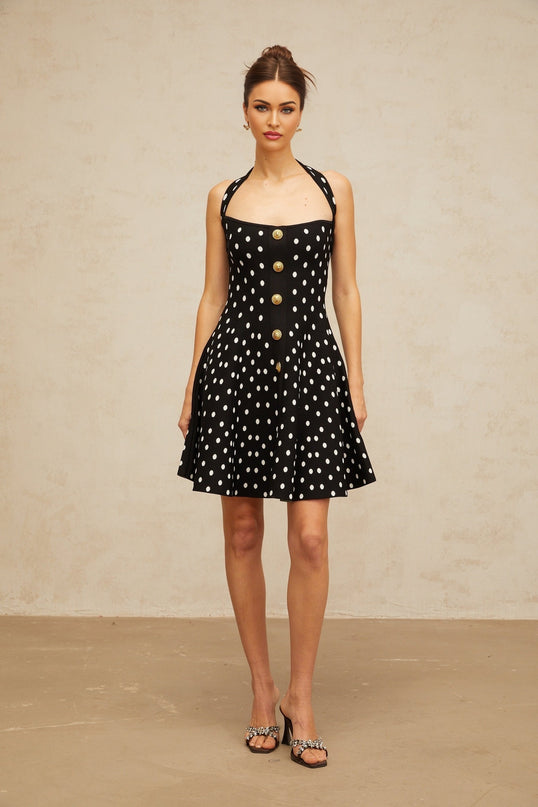 A black mini dress with white polka dots made of knit fabric featuring short sleeves and a fitted silhouette