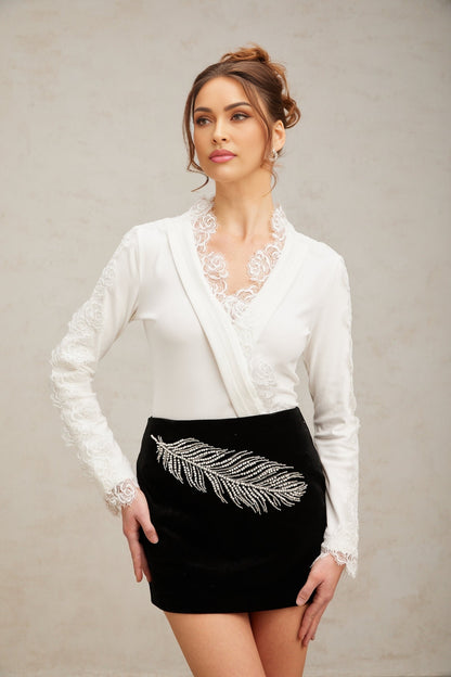 A black mini skirt with feather embroidery and embellishments featuring intricate detailing and a short hemline