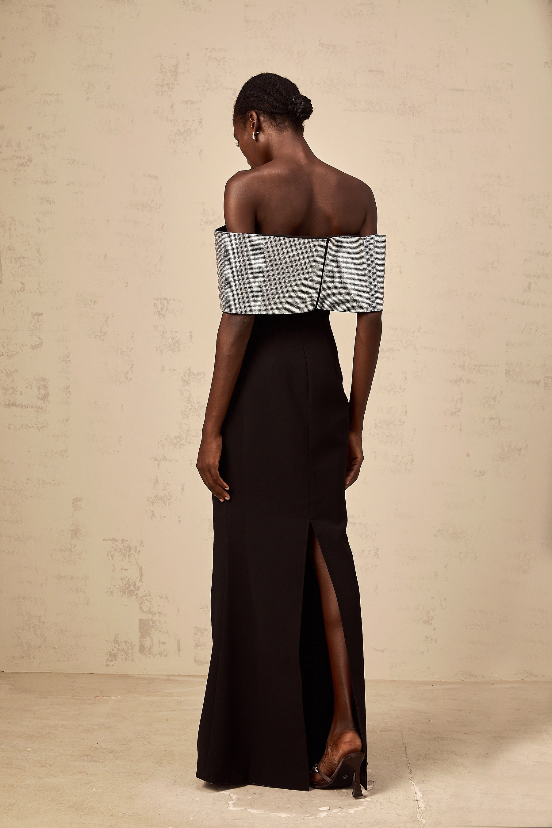 A black offshoulder maxi dress by Chloé featuring a rhinestone bow detail