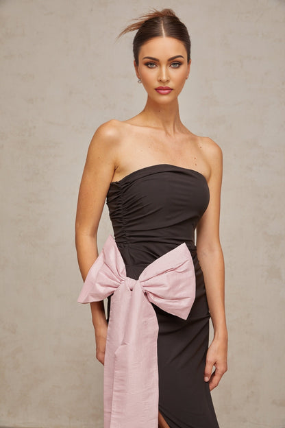 A black offshoulder maxi dress with a bow detail worn by a model against a plain background