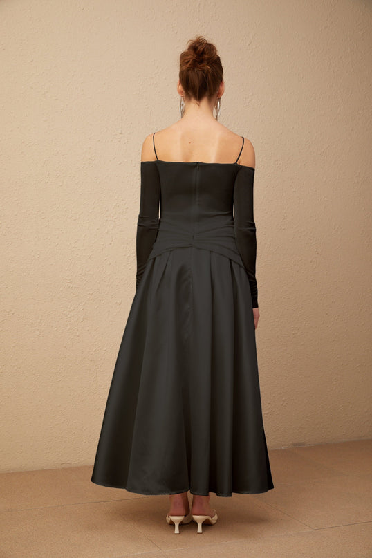 A black offshoulder maxi dress with panelled design worn by a model standing against a plain background