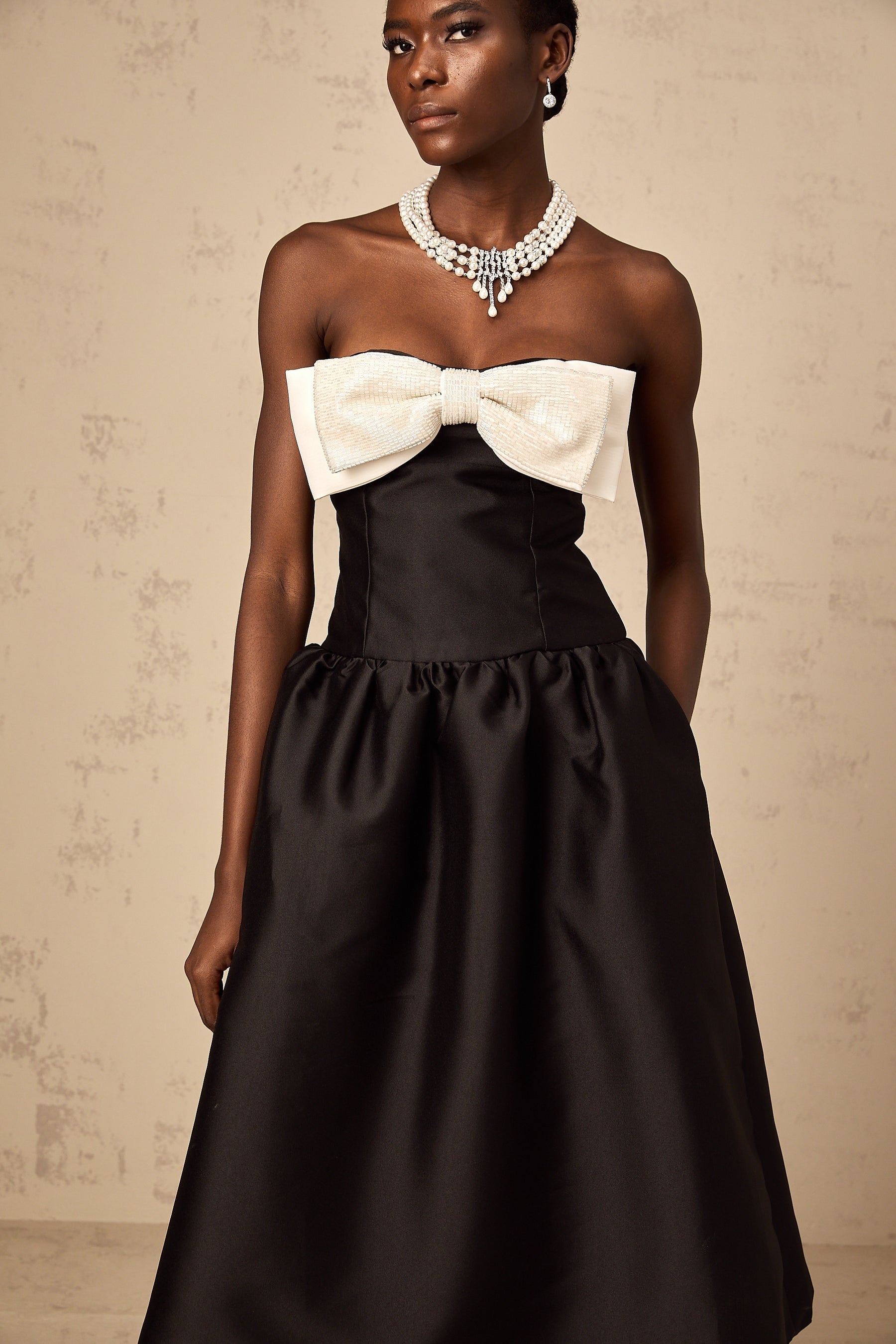 A black offshoulder midi dress made of georgette fabric featuring a bowknot detail