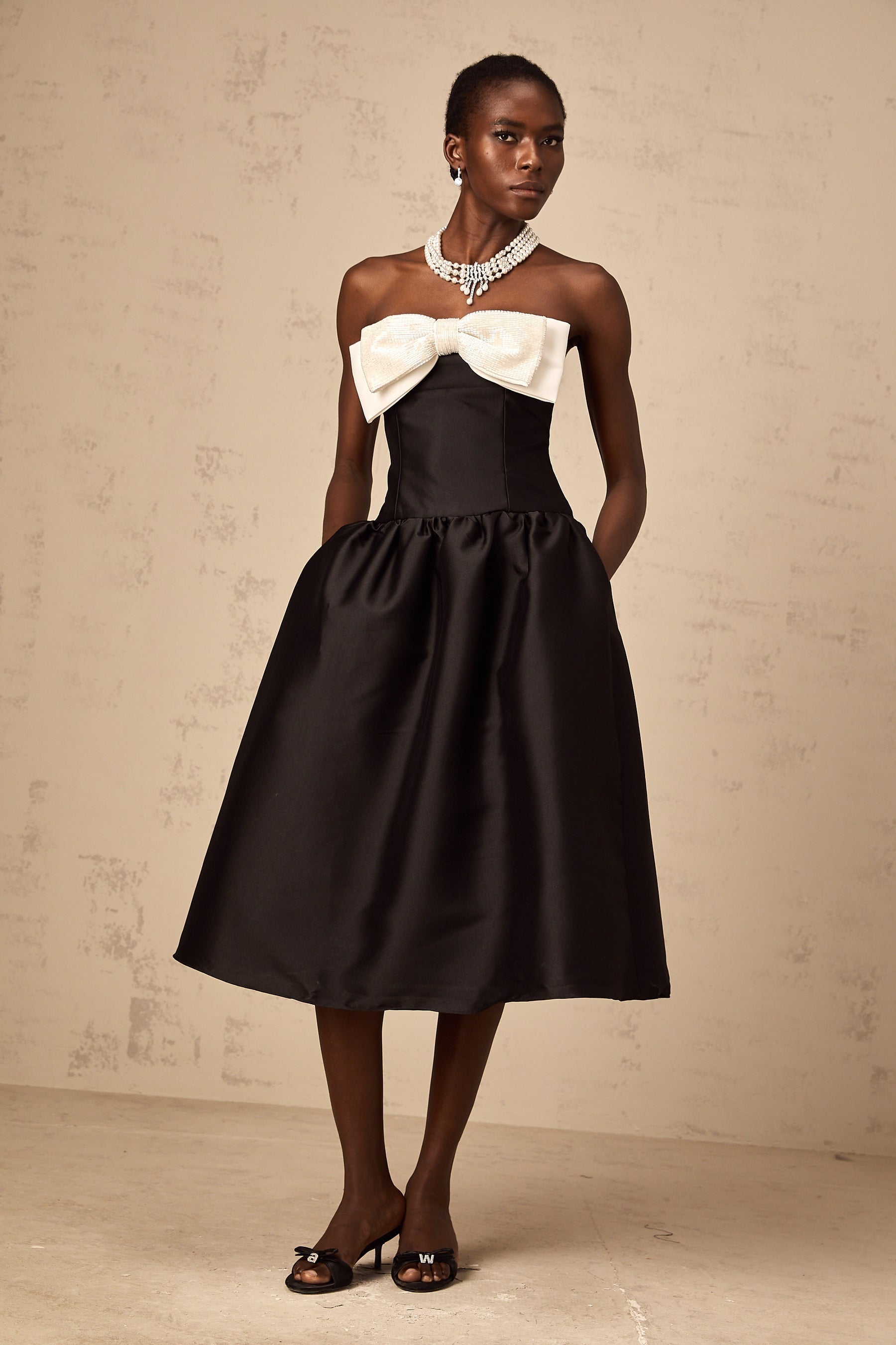 A black offshoulder midi dress made of georgette fabric featuring a bowknot detail