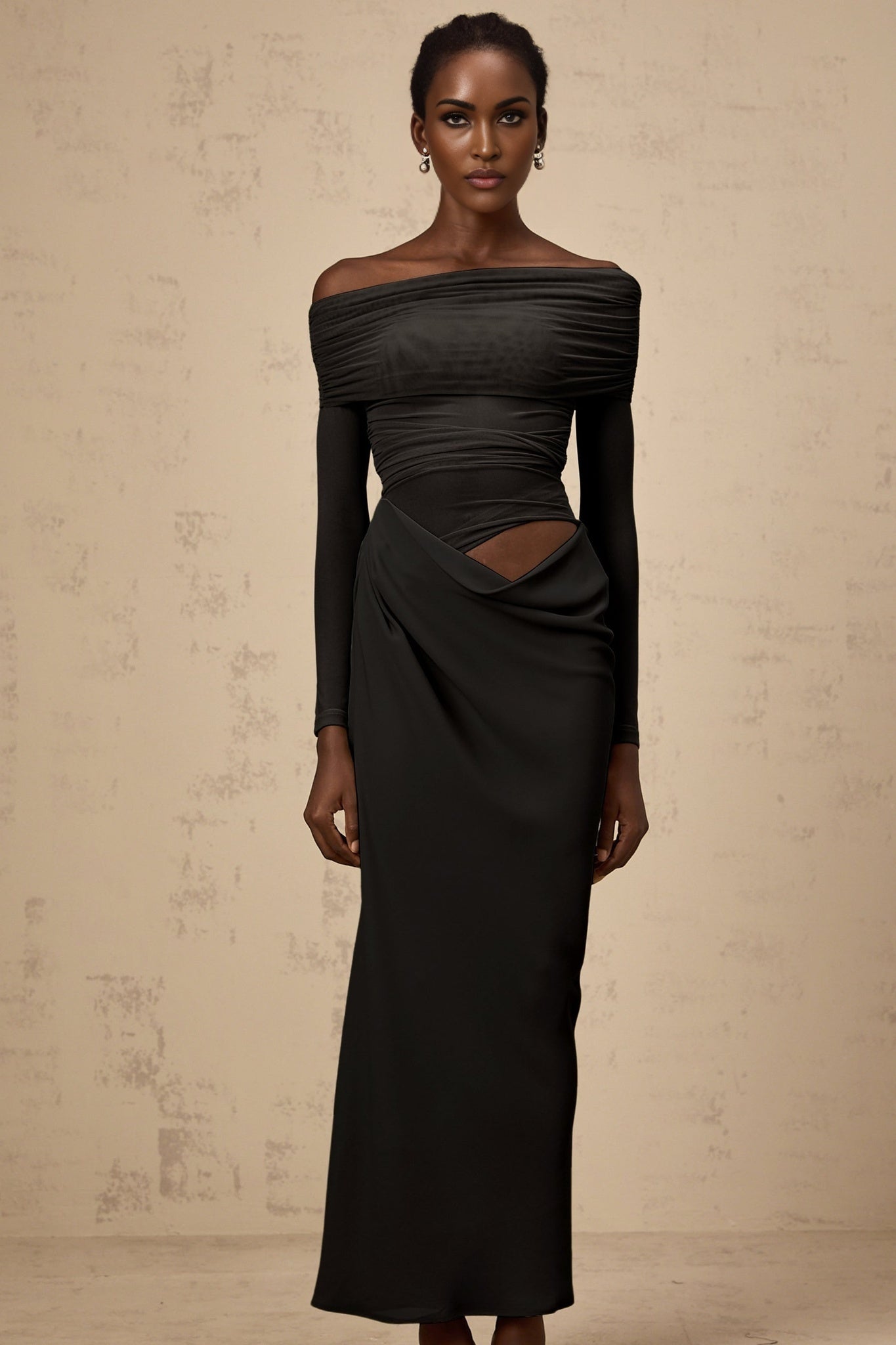 A black offshoulder midi dress with a semisheer design worn by a model standing against a plain background