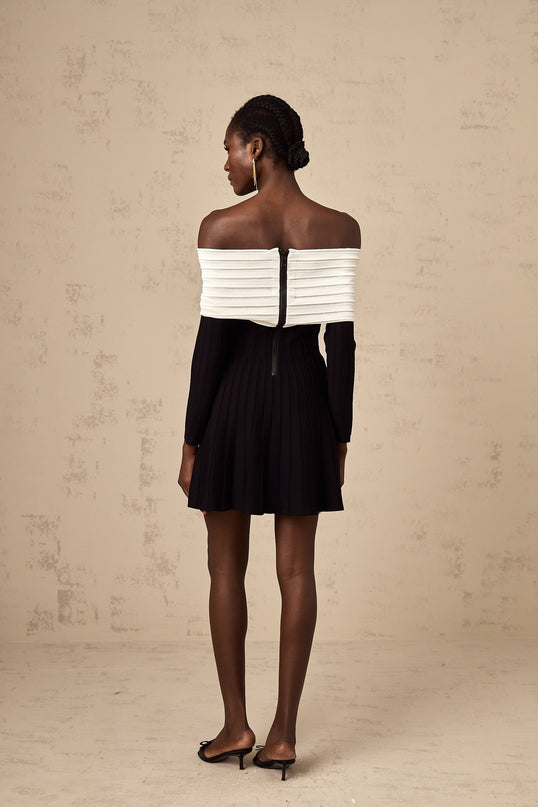 A black offshoulder mini dress with a bow detail and knit fabric worn by a model