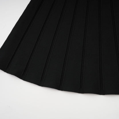 A black offshoulder mini dress with a bow detail and knit fabric worn by a model