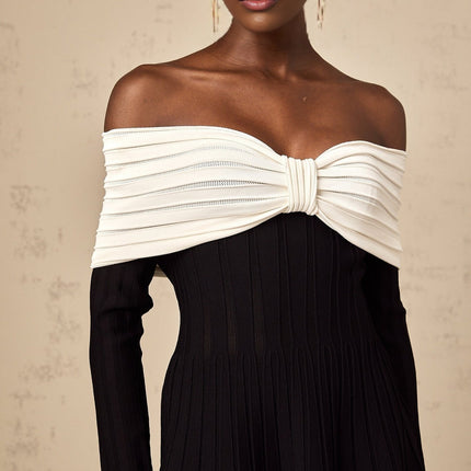 A black offshoulder mini dress with a bow detail and knit texture worn by a model