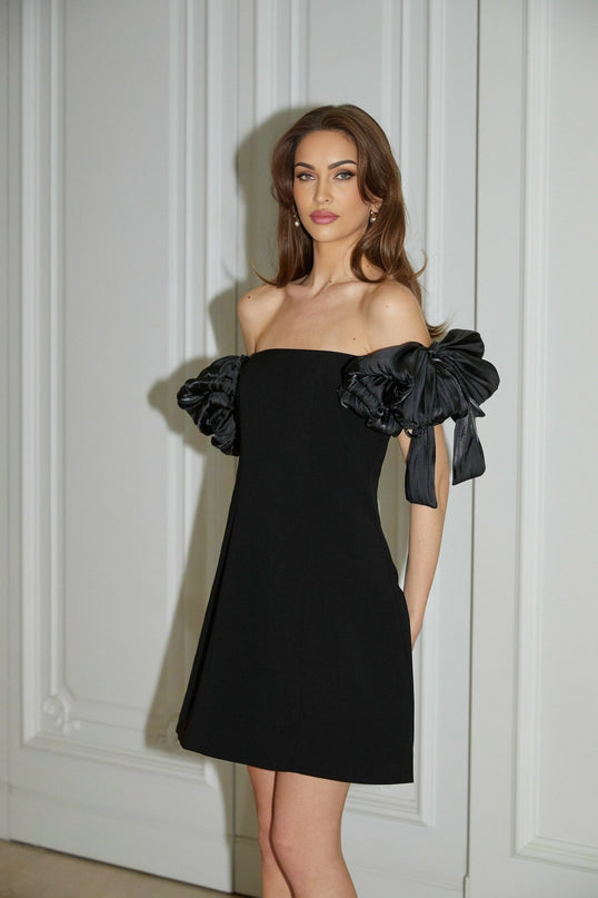 A black offshoulder mini dress with floral details named Erica worn by a model against a plain background