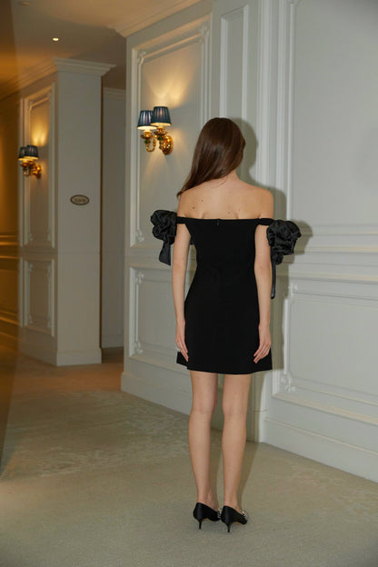 A black offshoulder mini dress with floral details named Erica worn by a model against a plain background