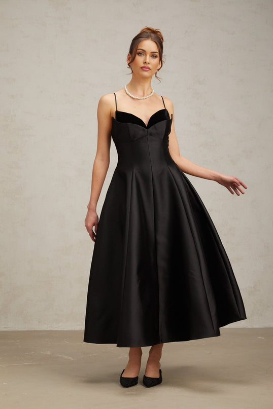 A black pleated midi dress with a flared skirt and fitted bodice named Roxane