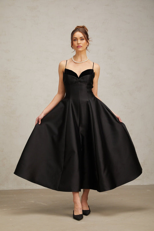 A black pleated midi dress with a flared skirt and fitted waist named Roxane