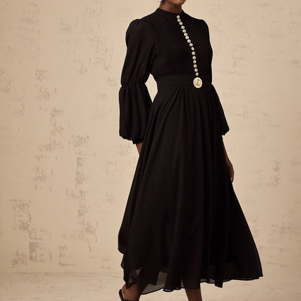A black pleated midi dress with button front closure and a sleek silhouette