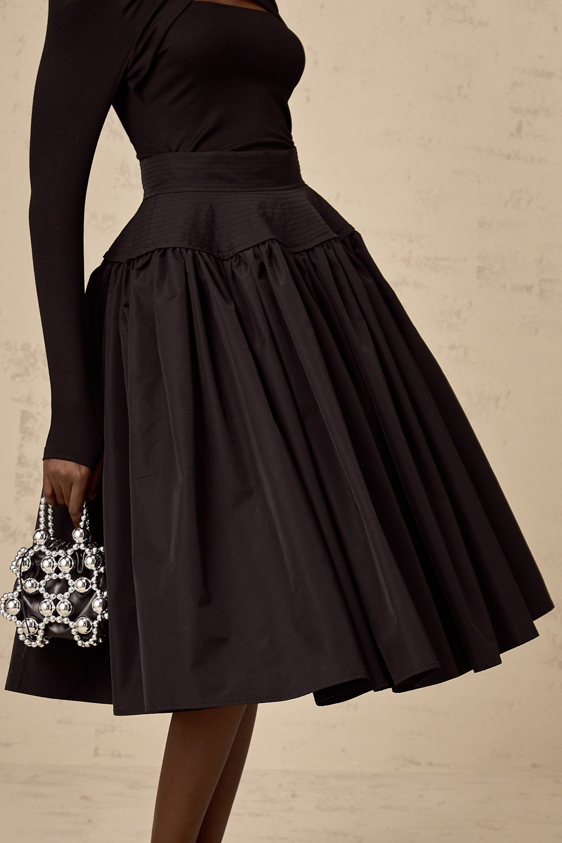 A black pleated midi skirt with a flared silhouette named Pauline