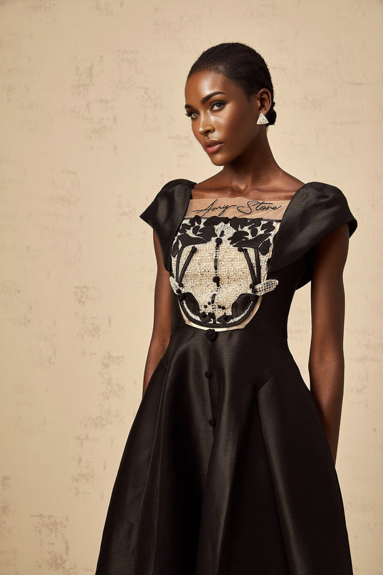 A black satin midi dress with floral applique details on an elegant sleeveless silhouette